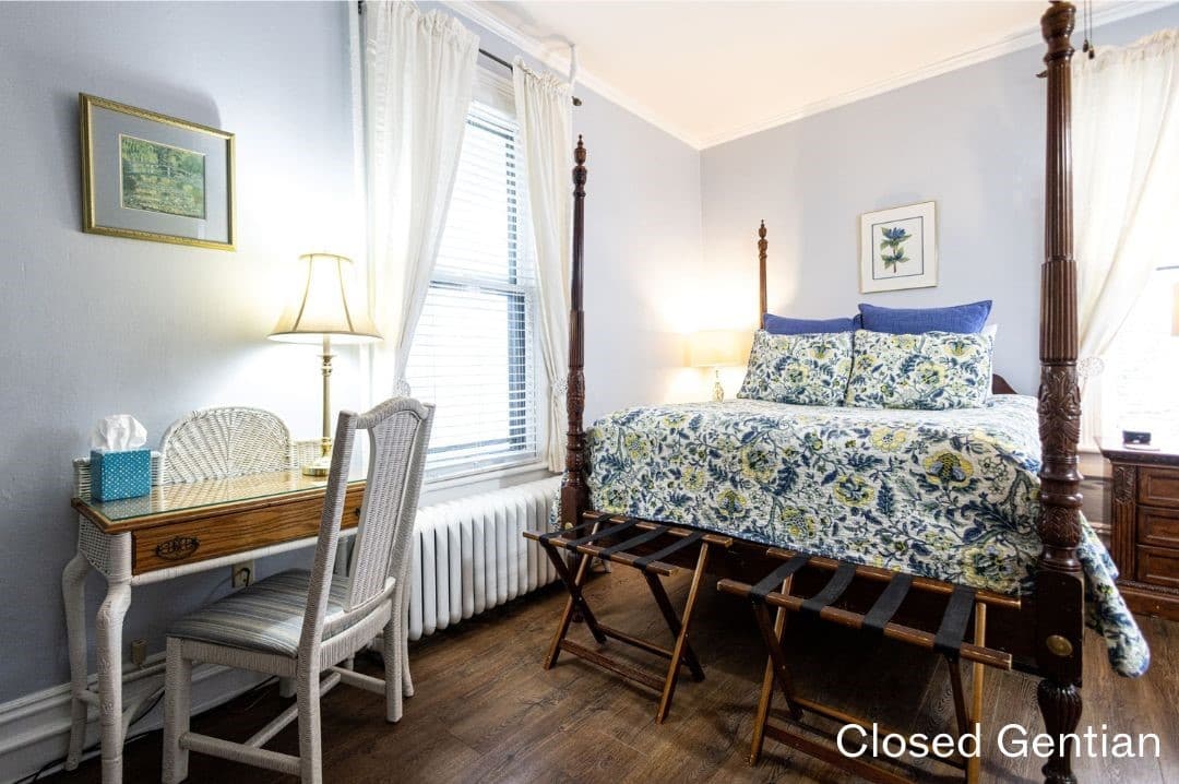 Room featuring a four-posted queen bed and a desk