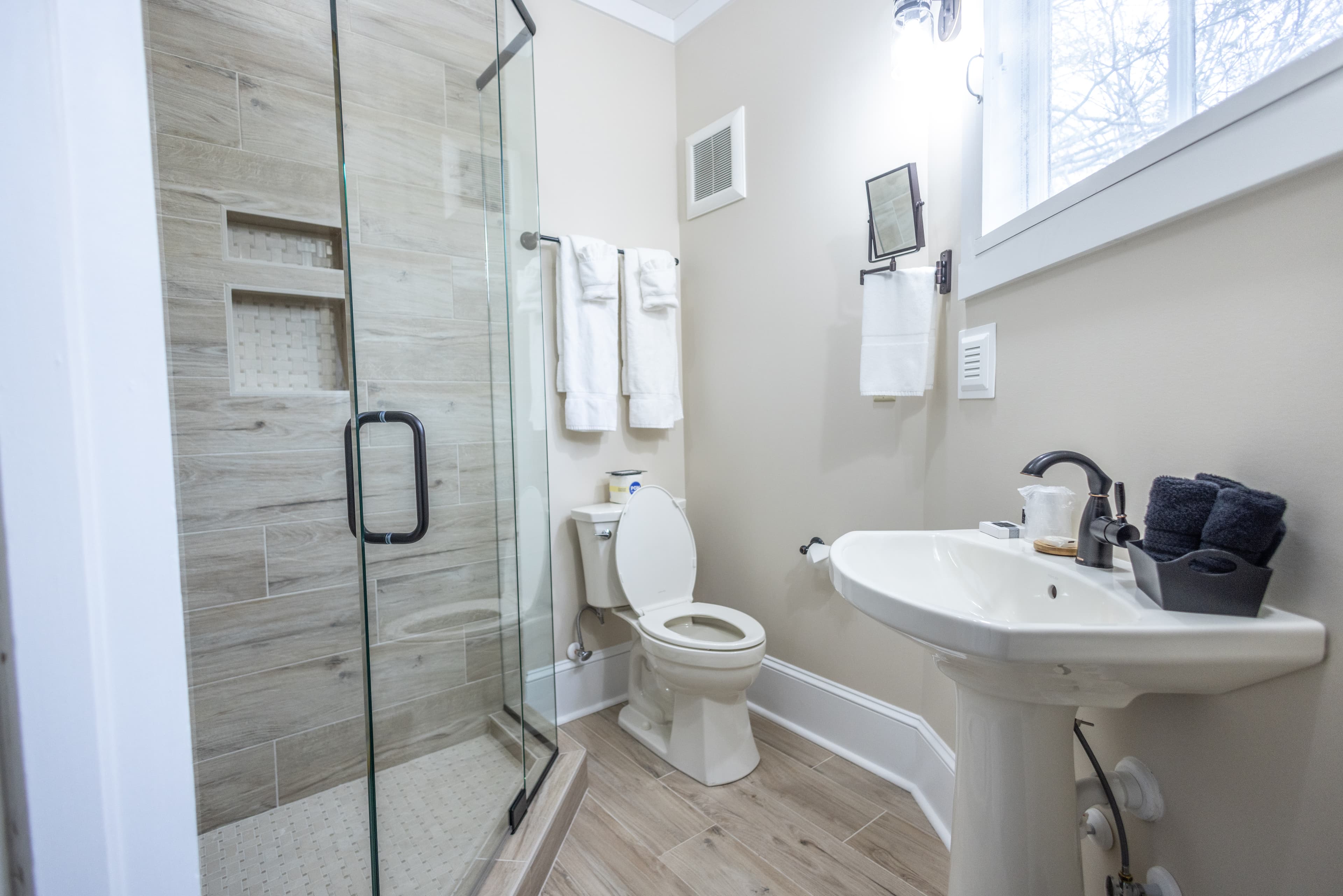 A compact bathroom featuring a glass shower, toilet, and sink with modern decor.