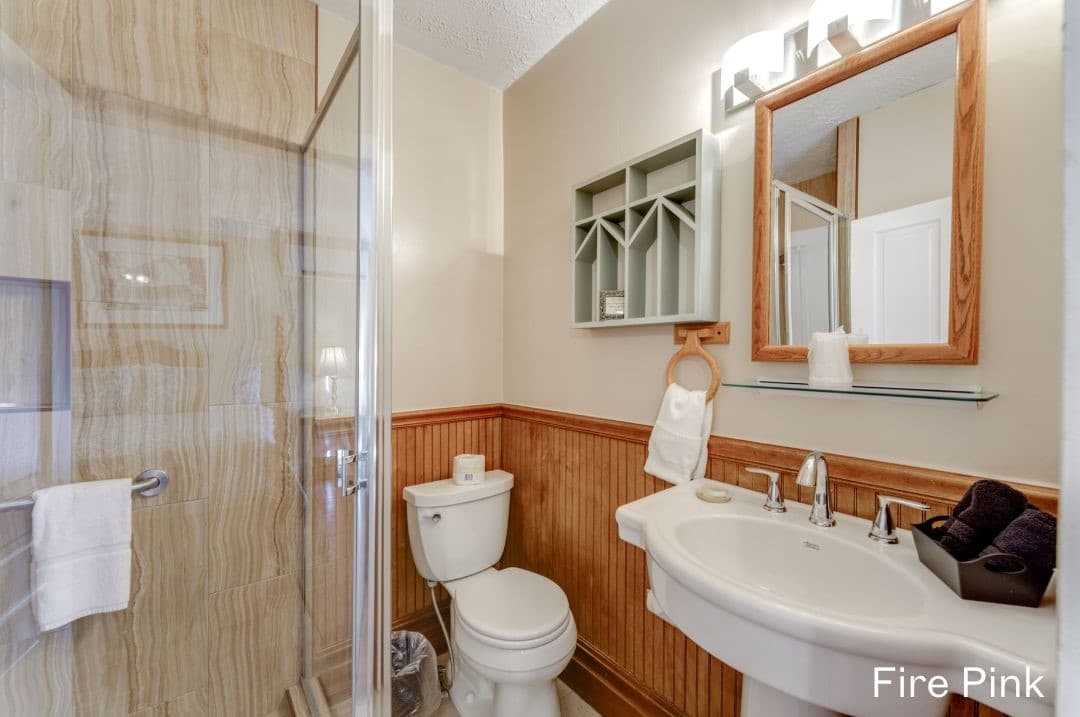 Fire Pink's bathroom features a large, tiled walk-in shower, a white pedestal sink, and a white toilet.