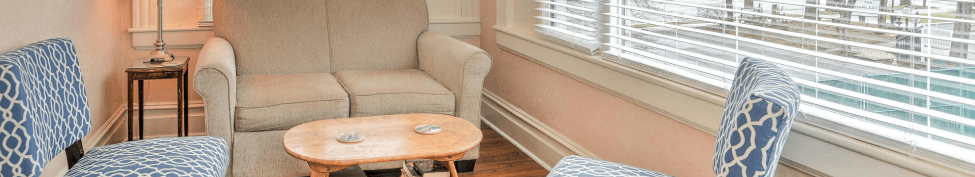 A cozy seating area featuring two patterned chairs and a light-colored couch beside a small wooden table.