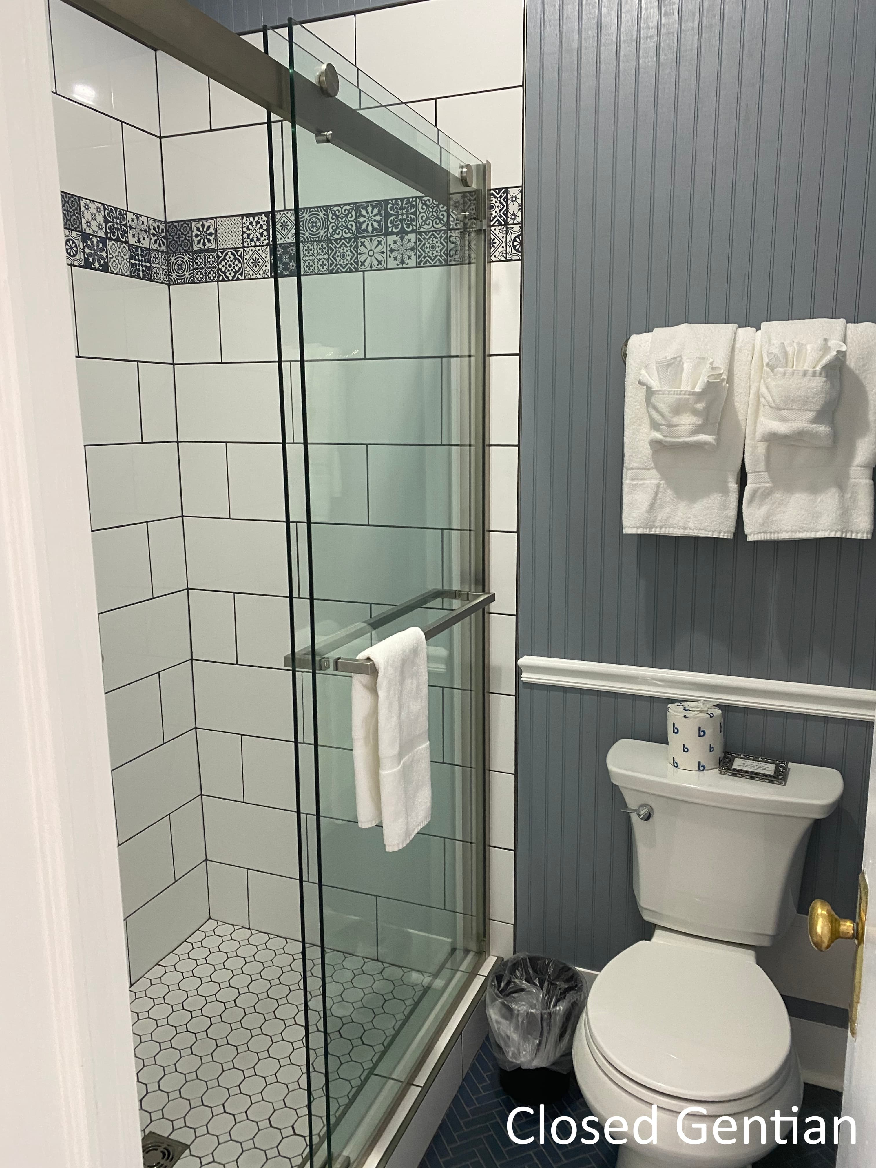 A clean bathroom featuring a glass shower enclosure, toilet, and neatly arranged towels.