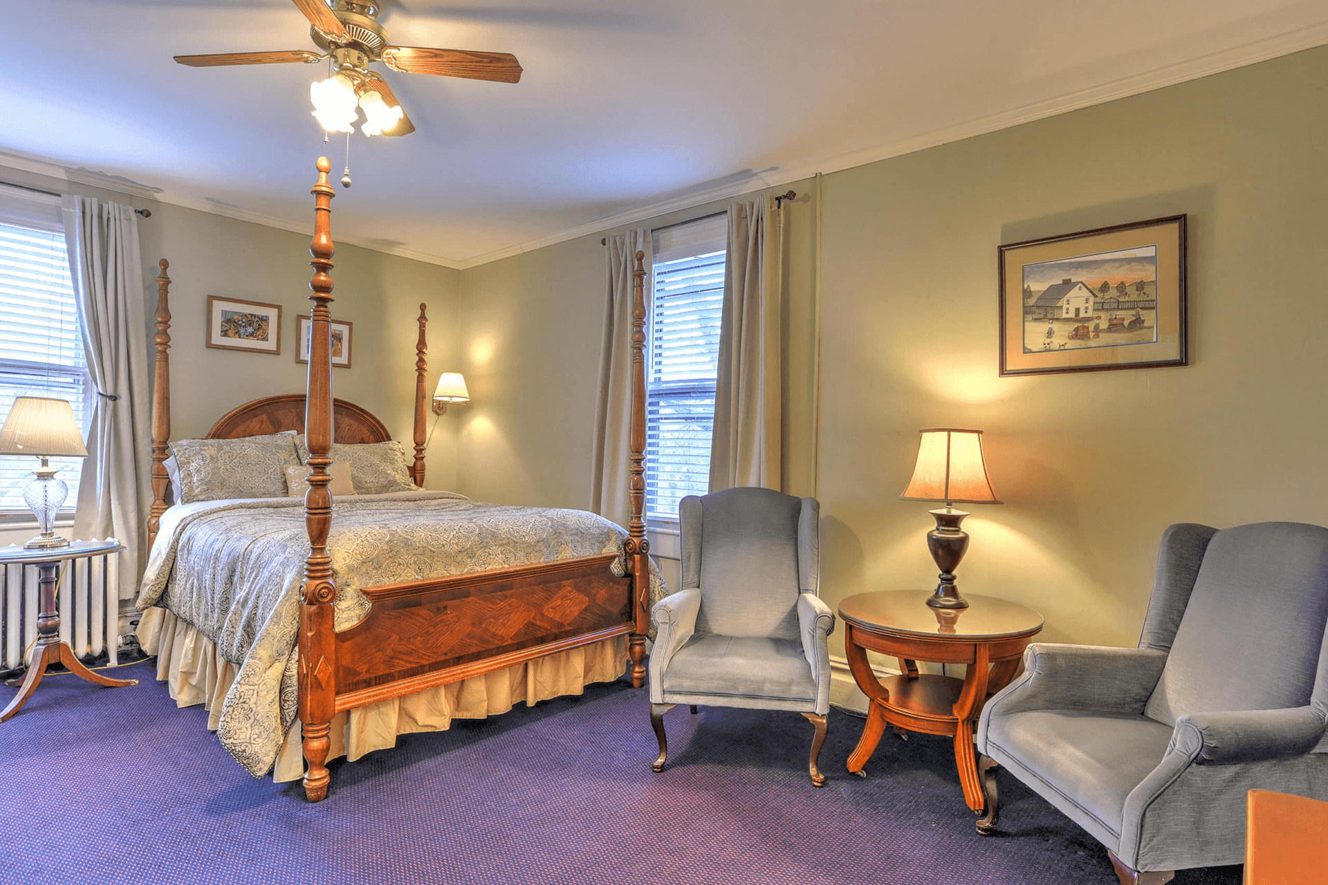 Cozy bedroom featuring a four-poster bed, armchairs, and natural light.