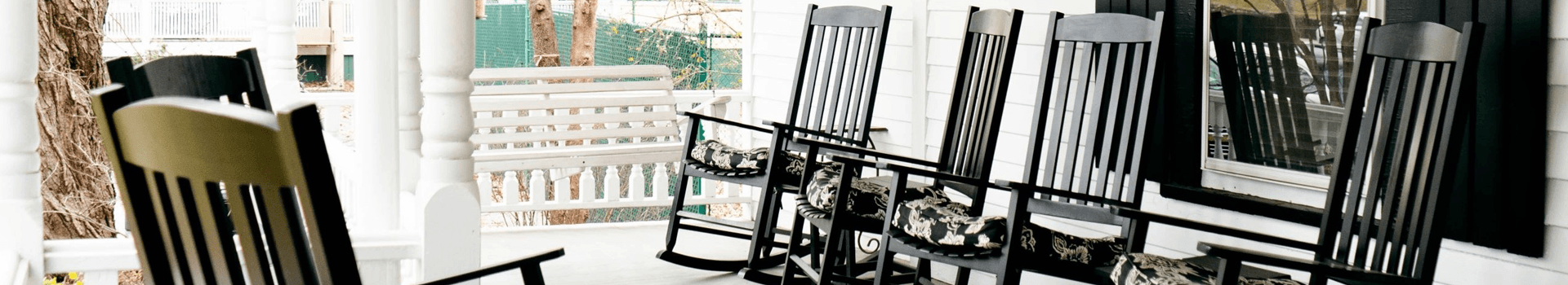 A row of black rocking chairs on a porch.