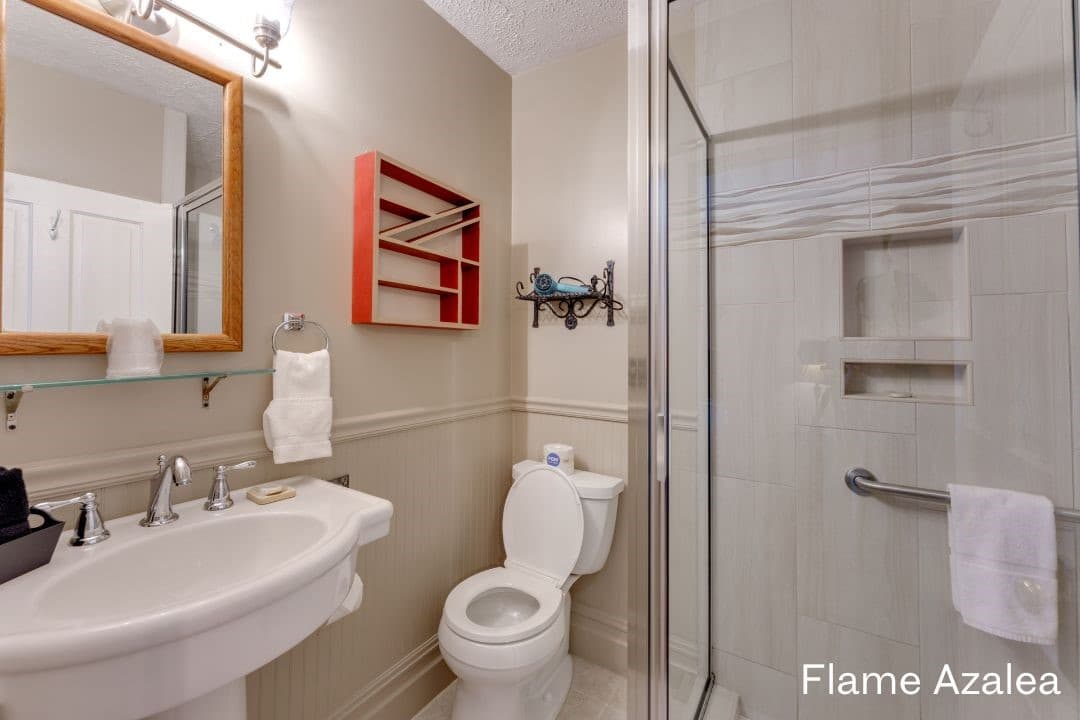 Flame Azalea's bathroom features a large, tiled walk-in shower, a white pedestal sink, and a white toilet.