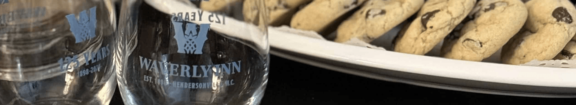 Two engraved glasses beside a plate of chocolate chip cookies.