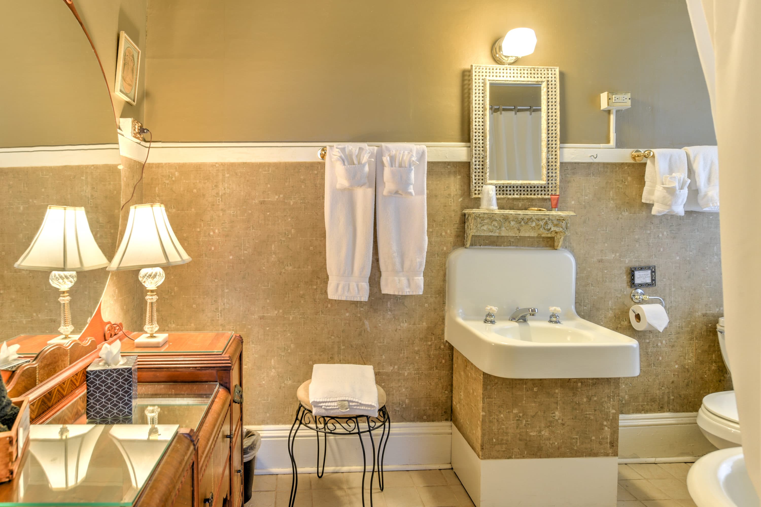 A stylish bathroom featuring a sink, decorative mirrors, fresh towels, and soft lighting.