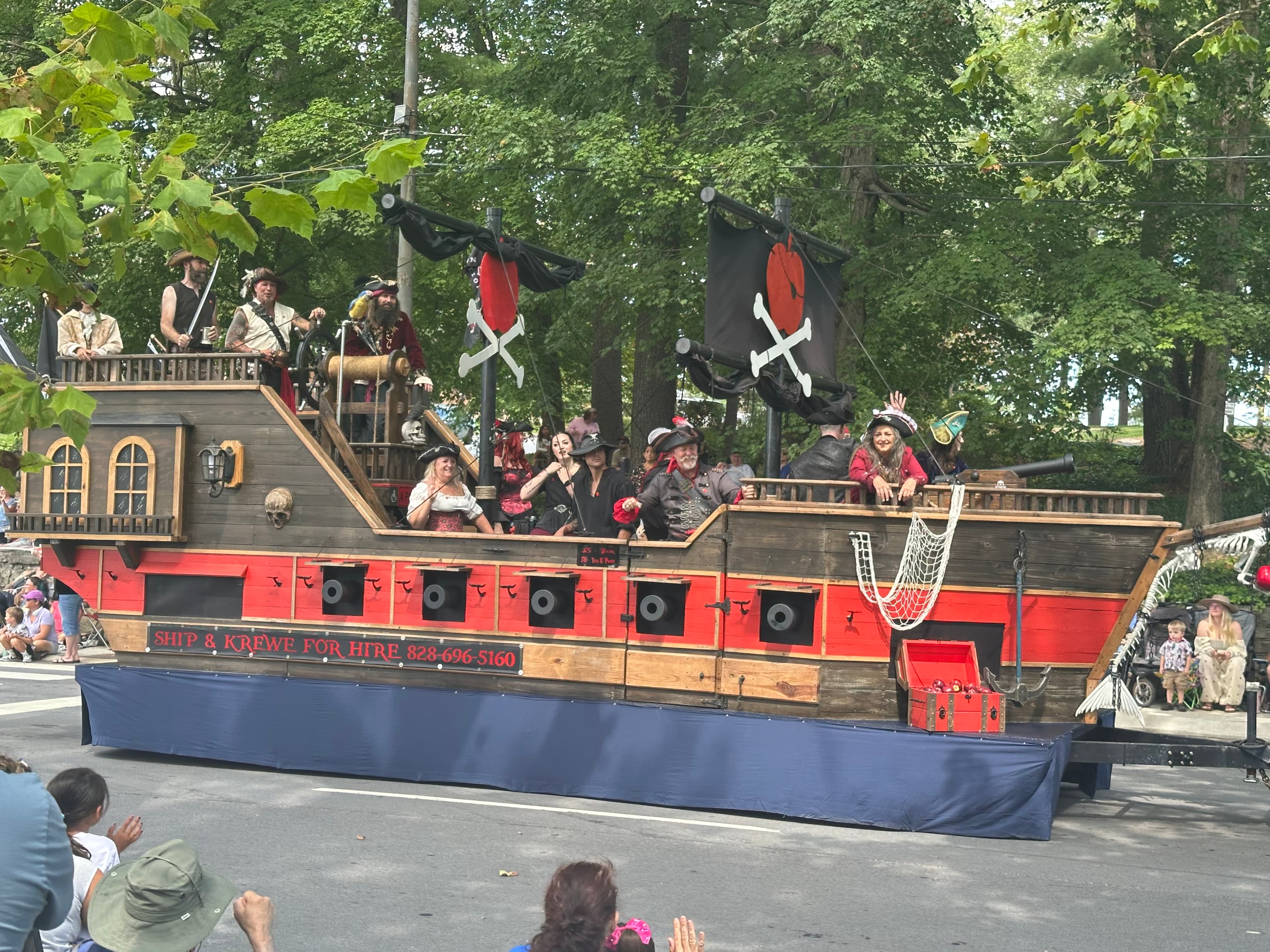 A pirate-themed float with performers in costume sails through a parade.