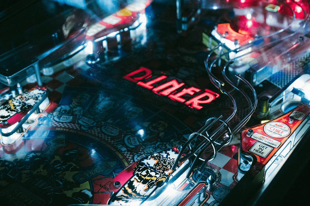 A close-up of a colorful pinball machine with the word "Diner" illuminated prominently.