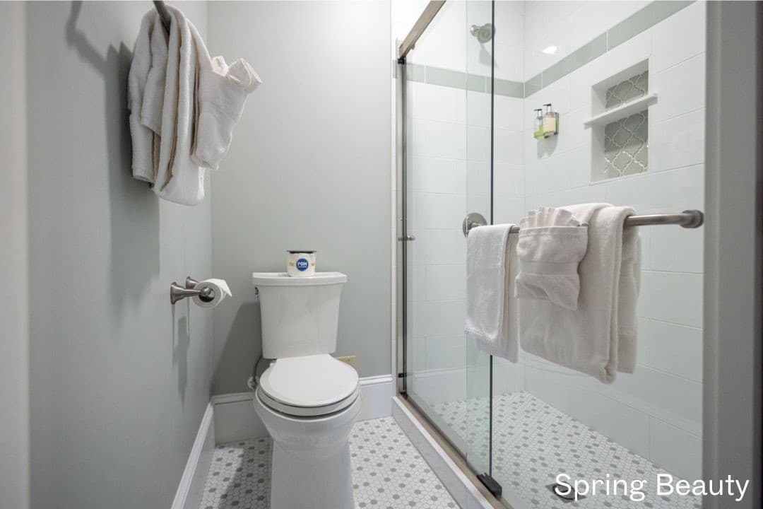 Spring Beauty's bathroom featuring a large, tiled walk-in shower, white toilet, and towel rack.