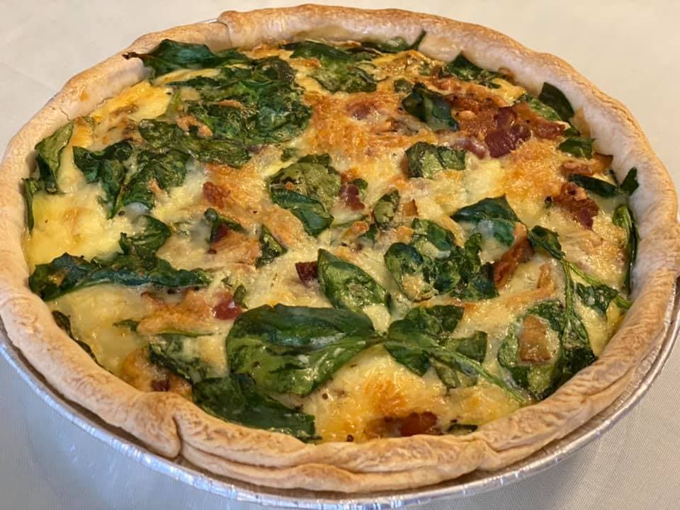 A golden-brown quiche filled with spinach and bits of bacon. A golden-brown quiche filled with spinach and bits of bacon.