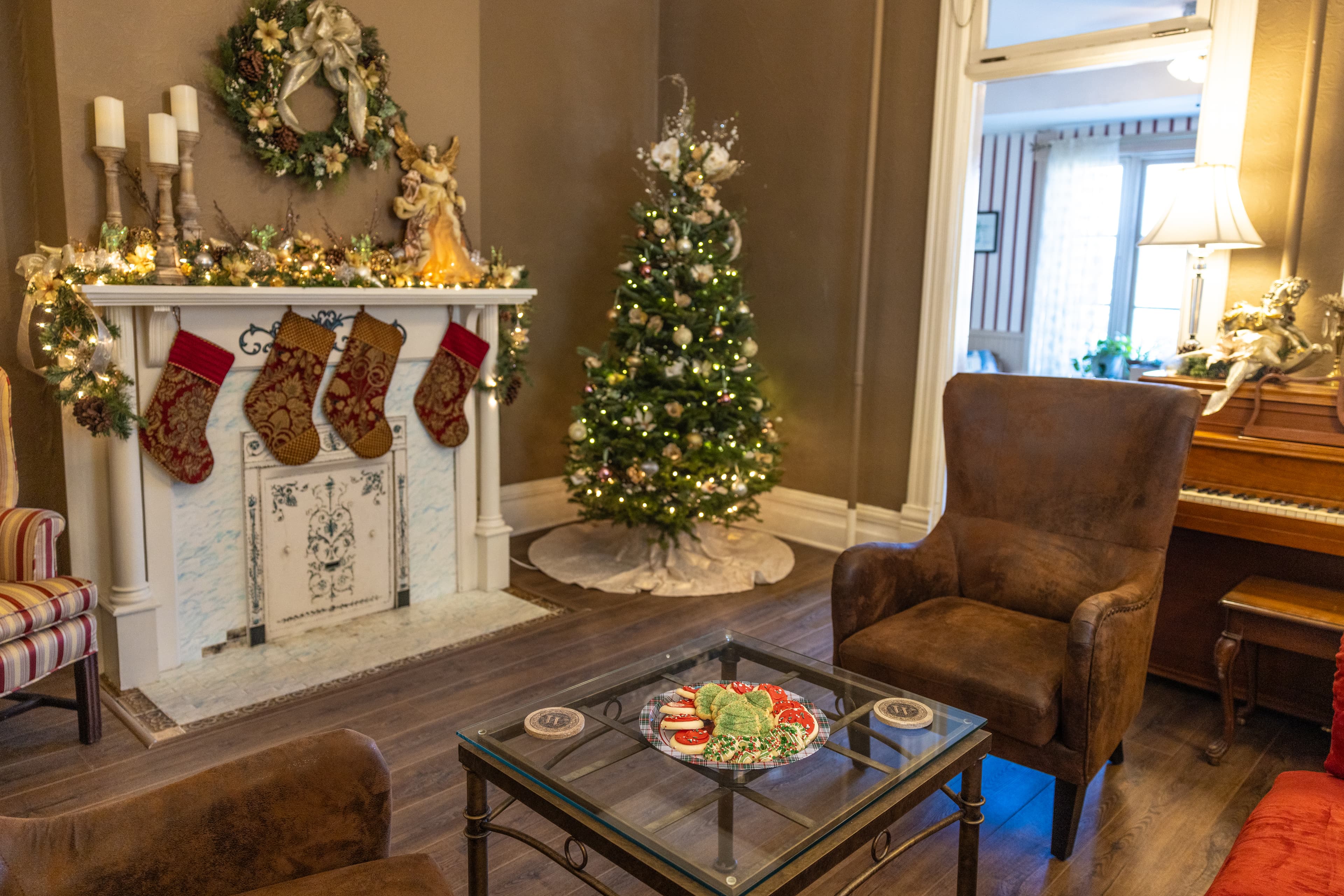 Cozy, festive living room with a decorated Christmas tree, stockings by the fireplace, and a glass coffee table.