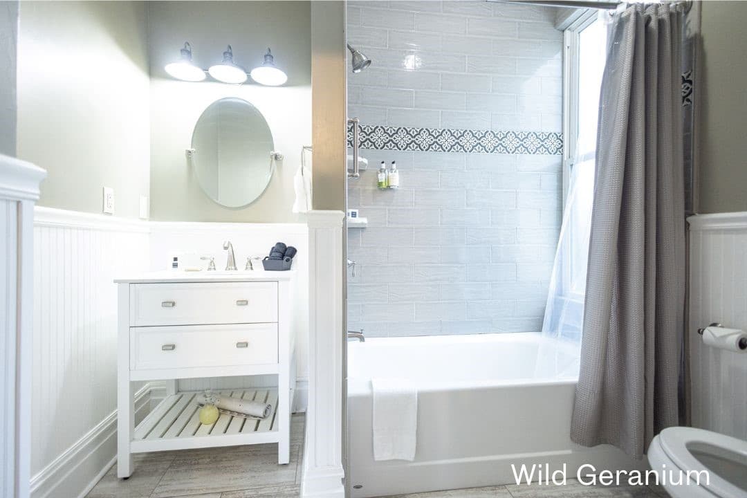 Wild Geranium's bathroom featuring a white sink and vanity, tiled shower/tub combo, and a white toilet.